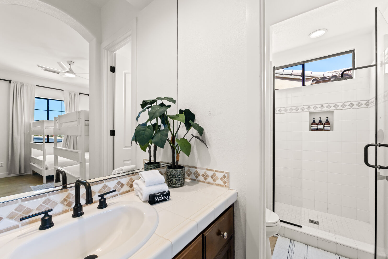 The private ensuite bathroom features a step-in tile shower with a built-in raised bench and a decorative vanity sink.