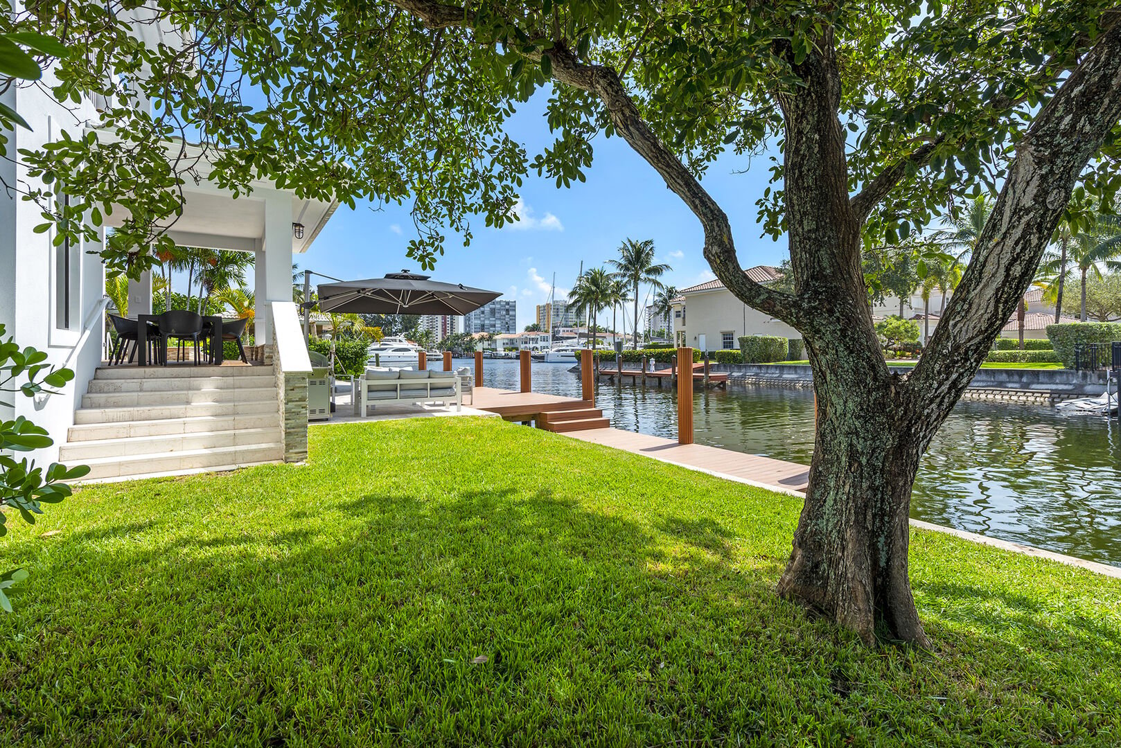 The lush backyard with the covered patio's dinning table, lounge area, heated pool and waterfront views.