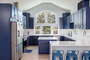 A cathedral ceiling kitchen with bold navy cabinets and marble countertops