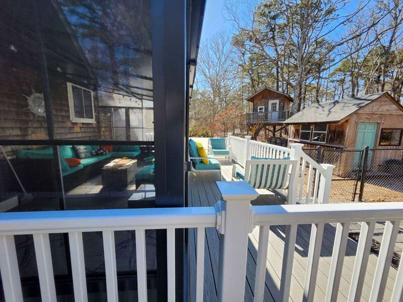 View of enclosed porch and adjoining deck space with treehouse in the distance - 14 Quail Nest Run Harwich Cape Cod-Hawksnest Hideaway-NEVR