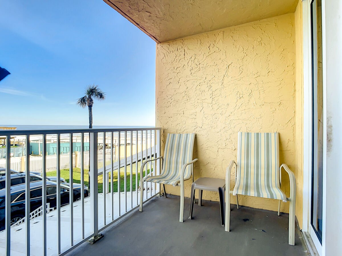 Balcony with seating and partial view of the ocean.