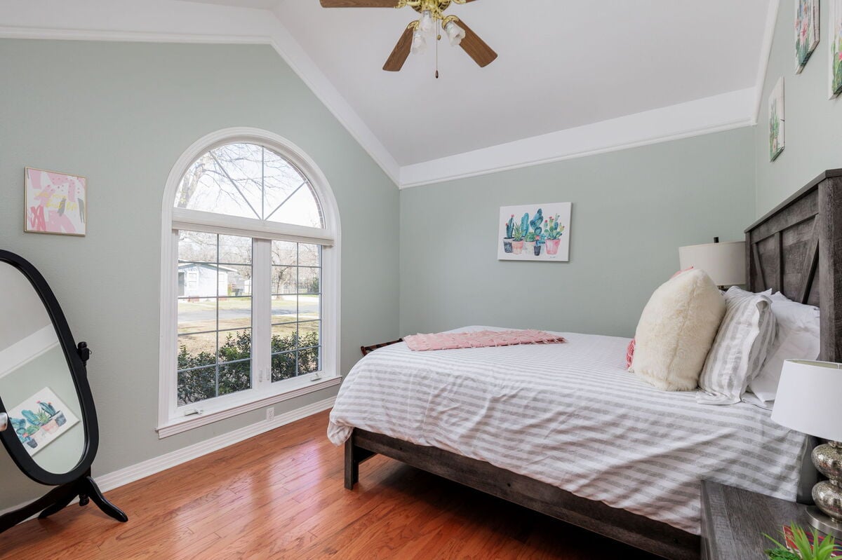 Enjoy the tranquil vibe of this charming bedroom adorned with artistic touches and a view that overlooks the peaceful neighborhood.