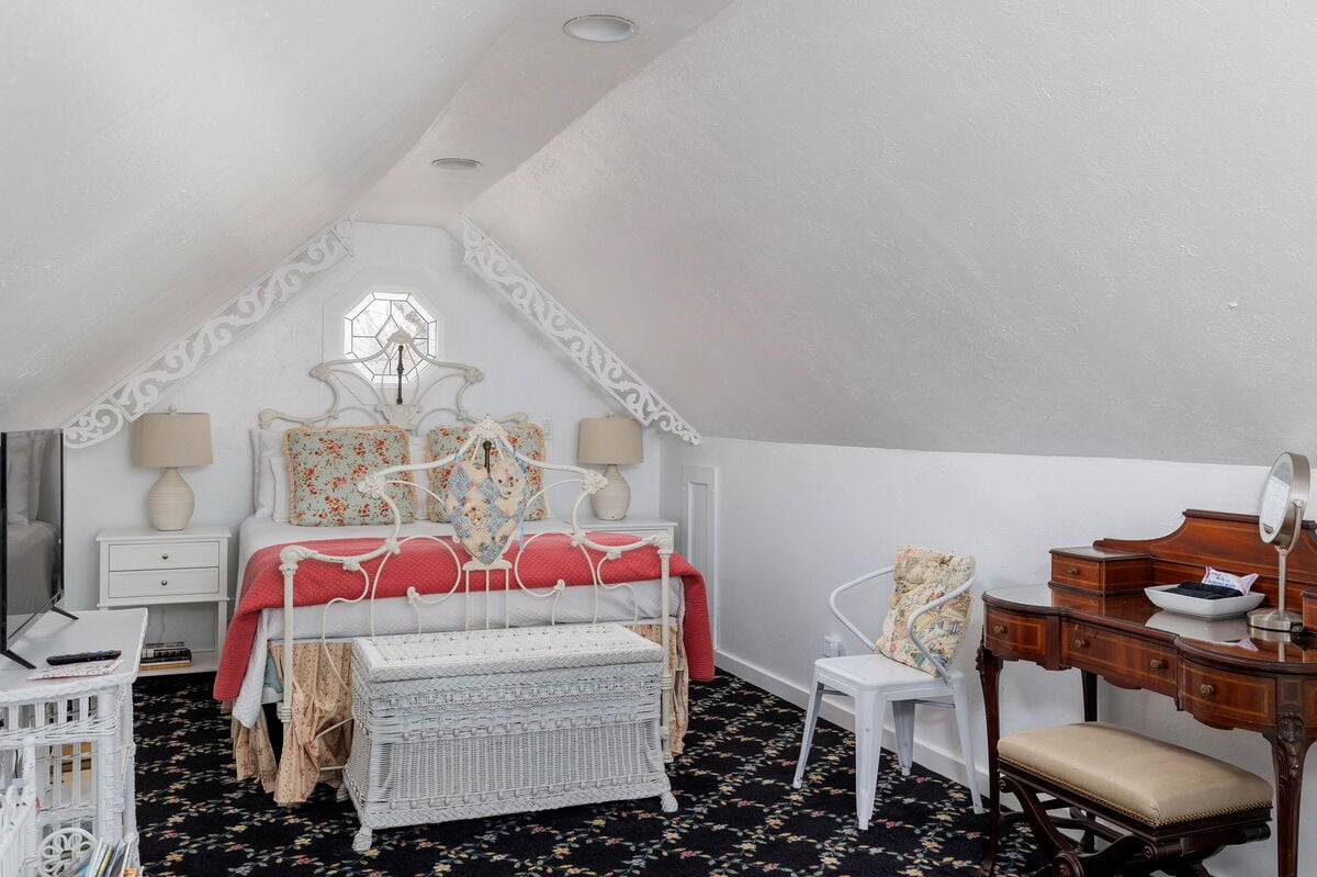 Relax in the cozy comfort of this Bedroom, featuring a custom-made queen-sized wrought iron bed adorned with plush bedding for a restful night's sleep
