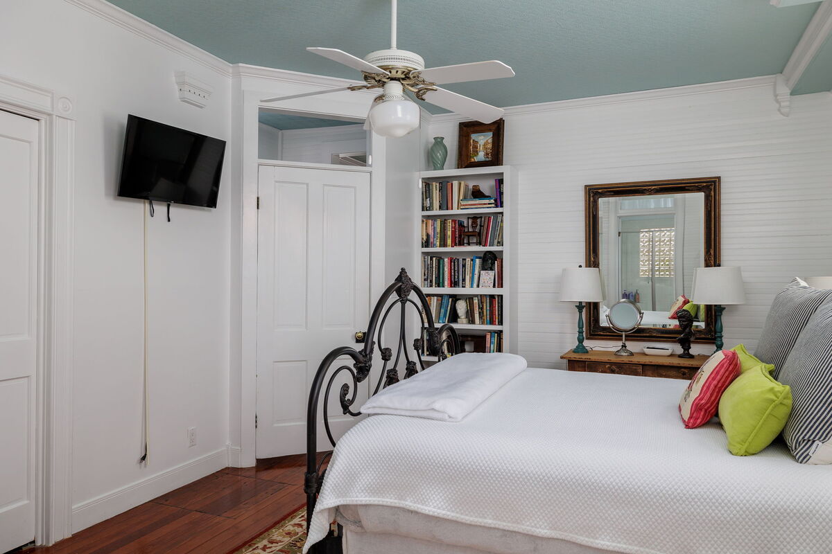 Experience peaceful slumber in this bedroom, furnished with a queen bed and bathed in natural light from the nearby windows for a bright and airy feel