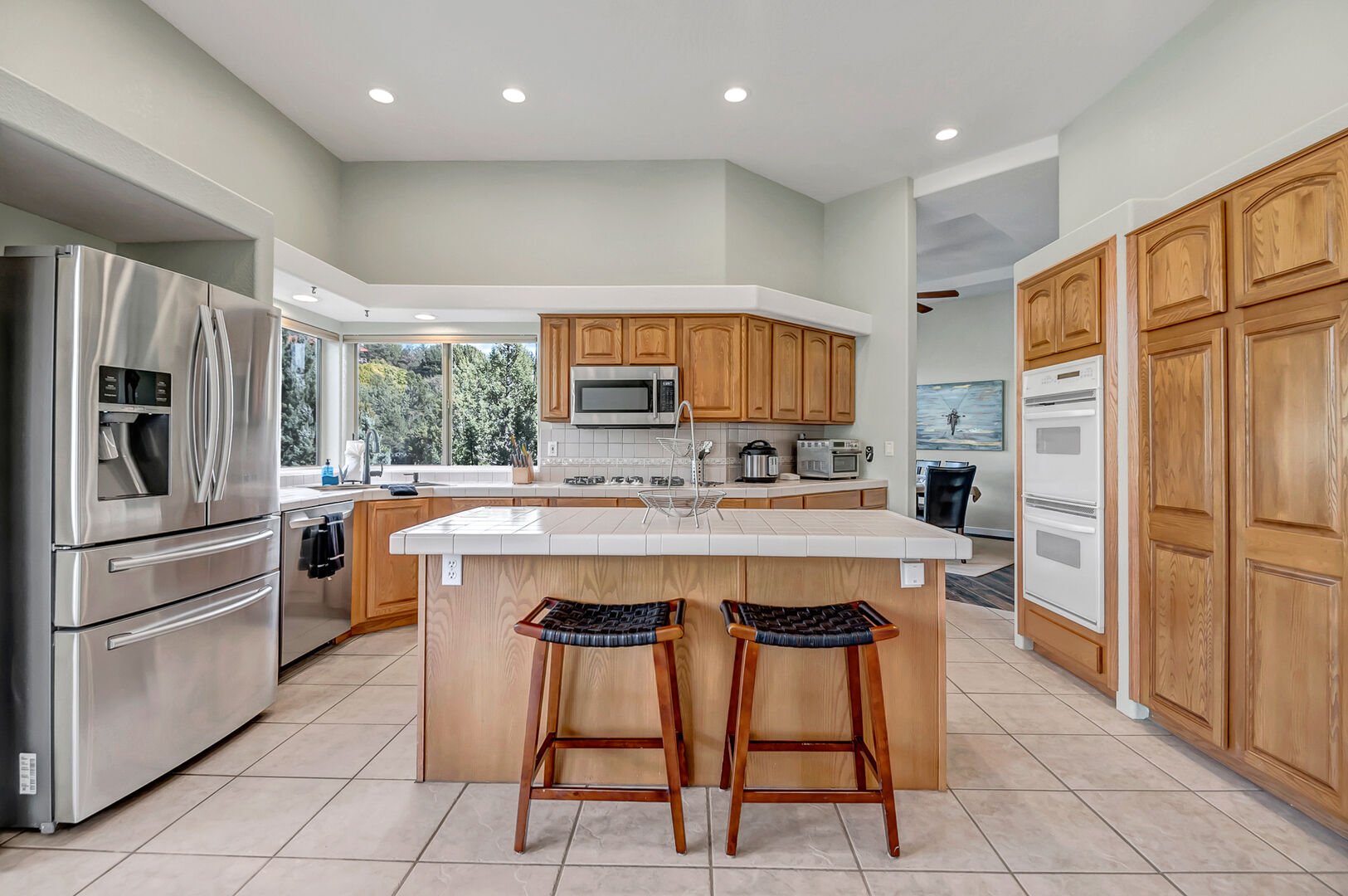 Fully equipped kitchen boasts high-end appliances, a 5-burner gas stove, and island seating for two
