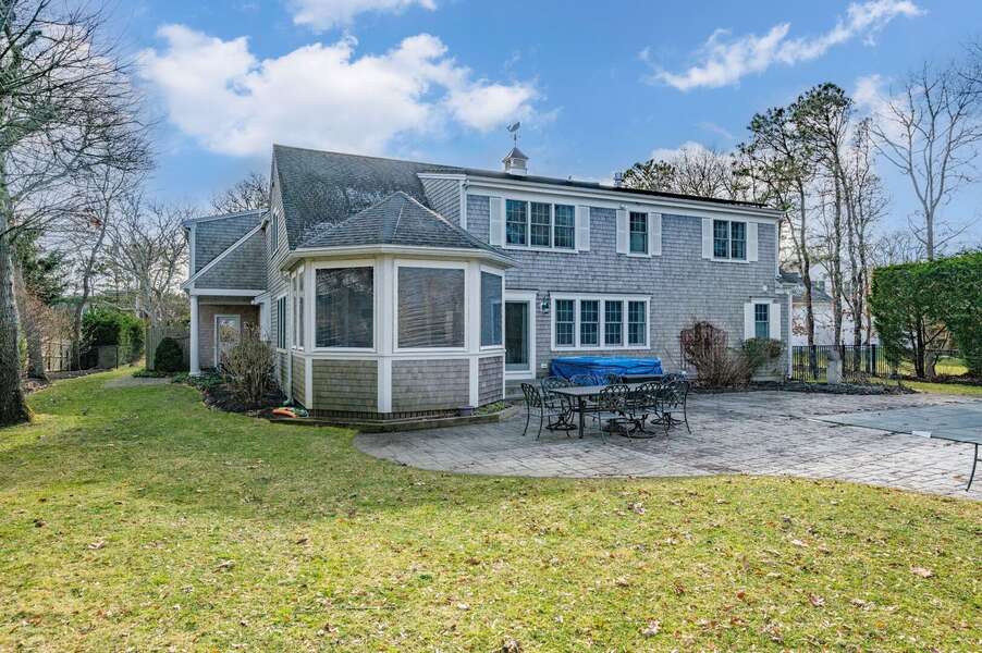 View of exterior including the sunroom, hot tub and patio dining set near the pool (new photos to come in the Spring when plantings are in bloom!) - 92 Hoyt Road Harwich Port Cape Cod - Apricari - NEVR