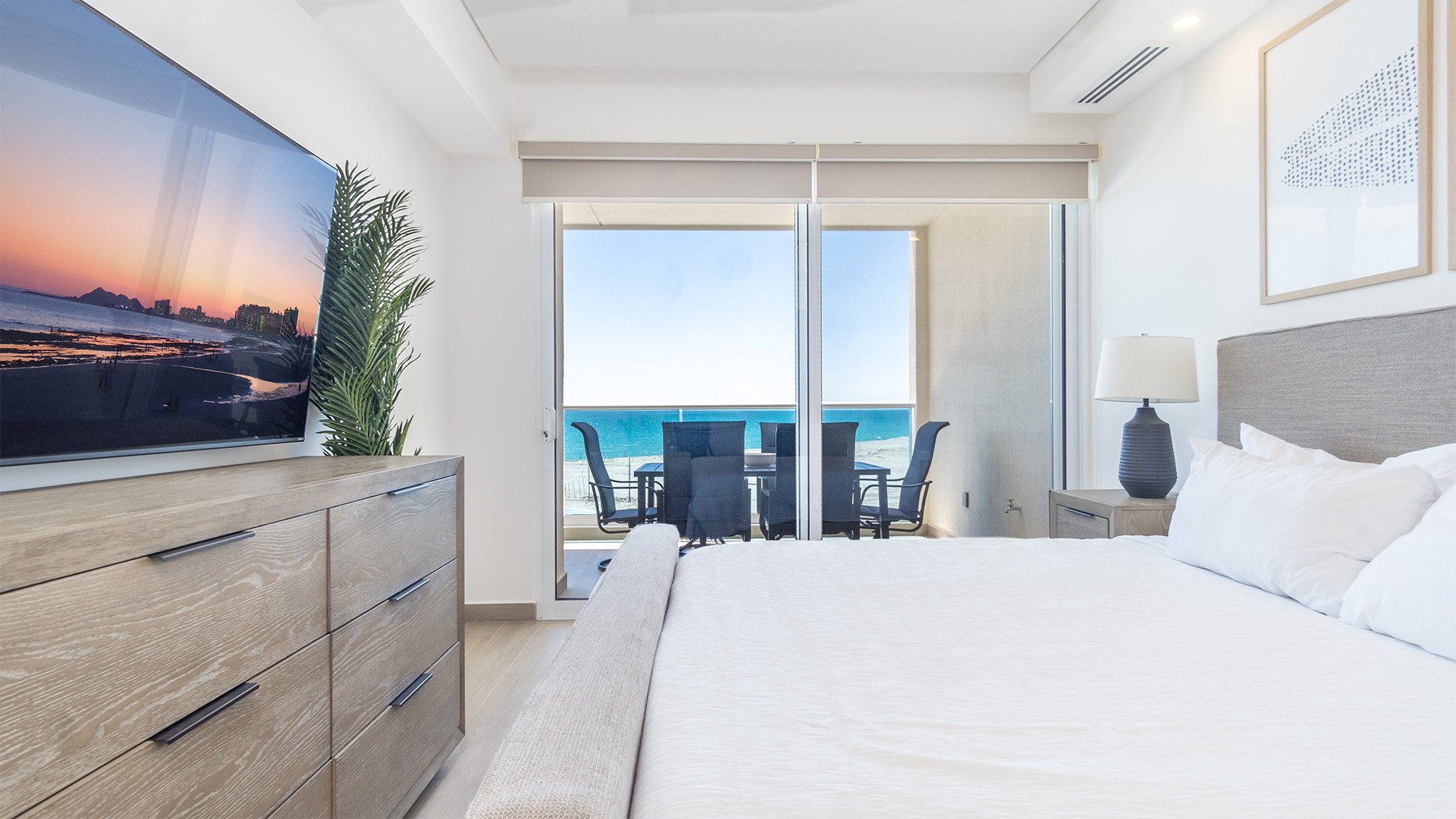 The master bedroom with TV, balcony access, dresser, and king bed.