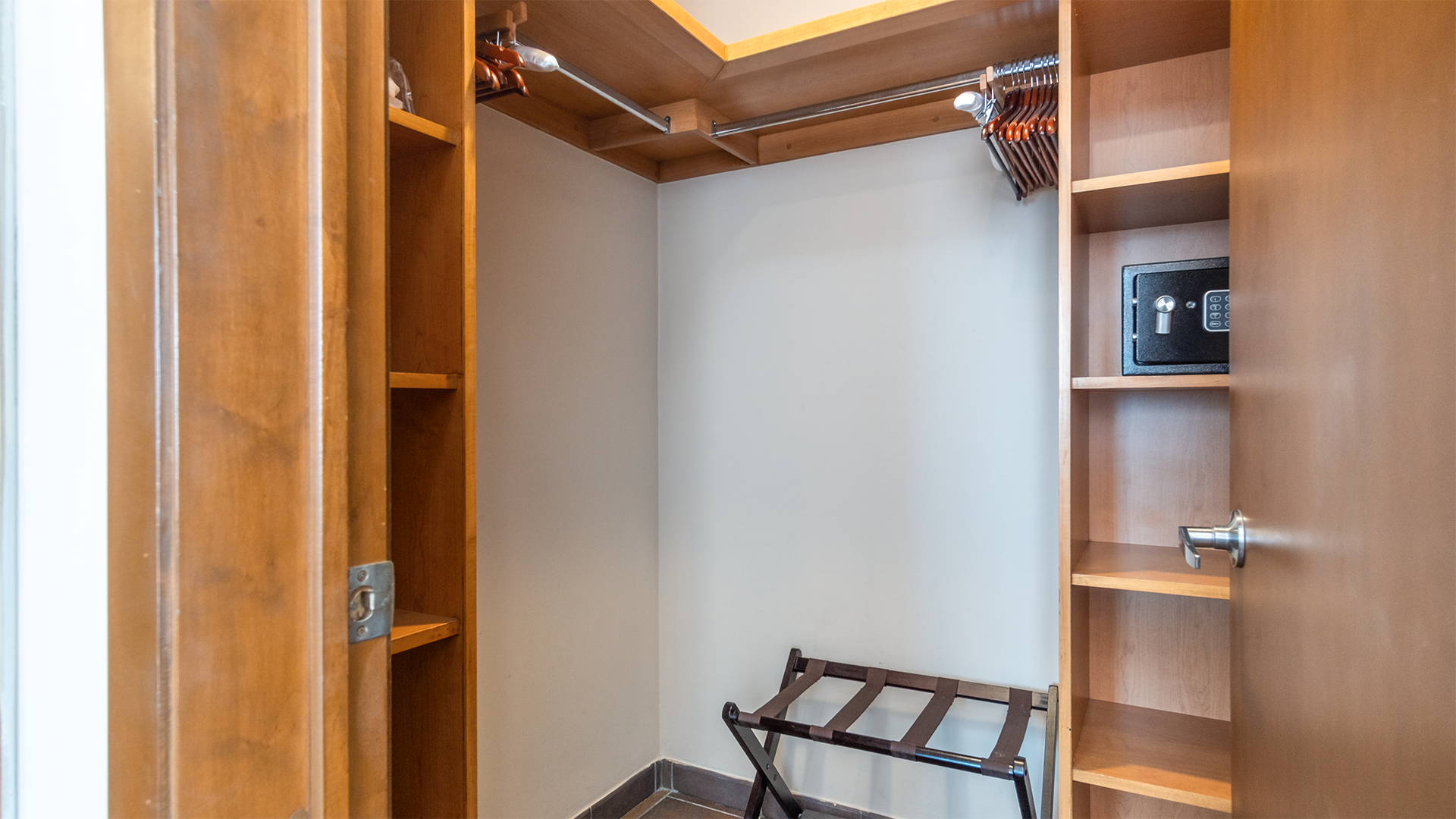 A walk in closet with shelves and a safe are part of the master bedroom.