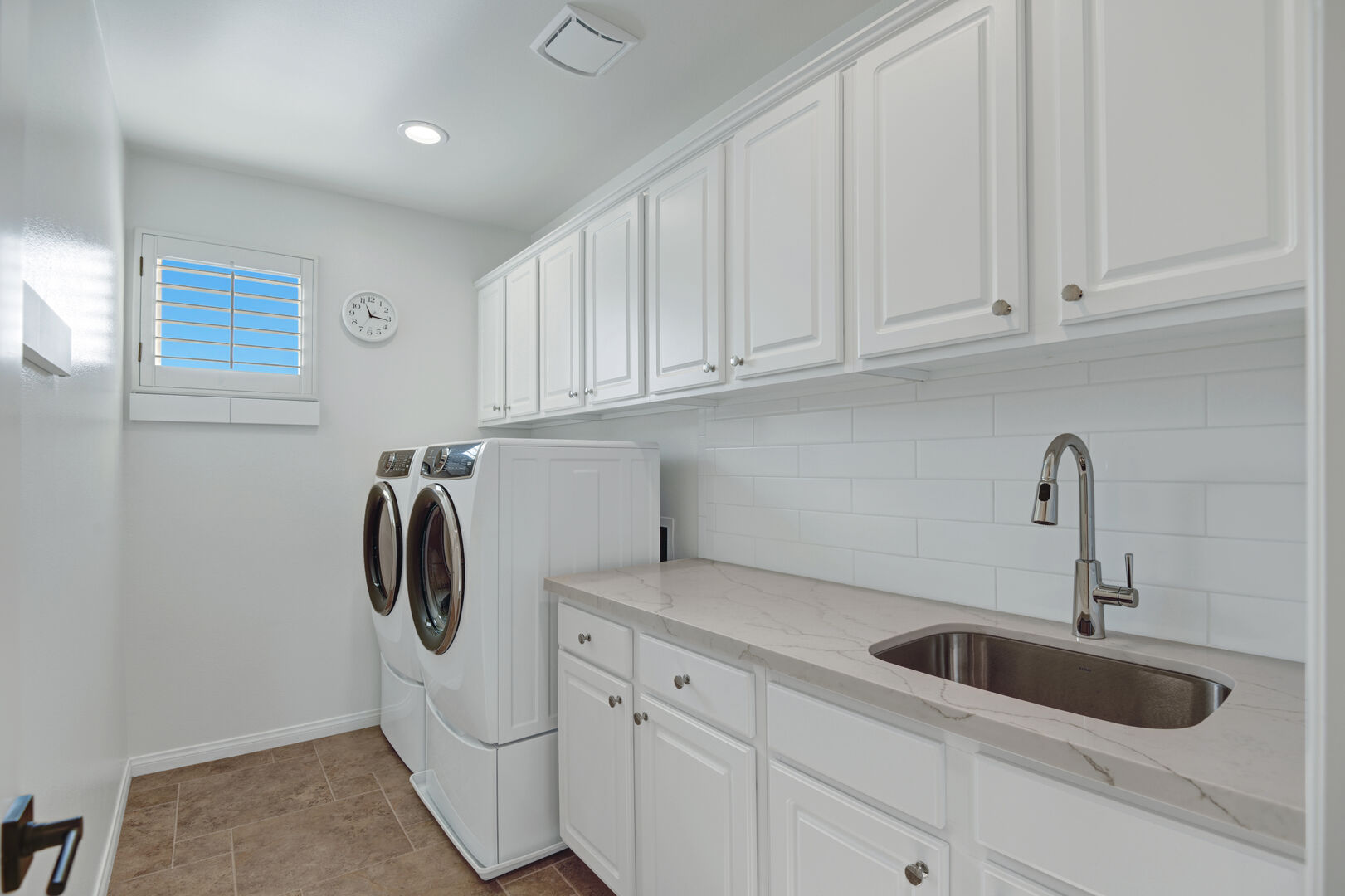 The laundry room is complete with matching washer and dryer, ample cabinet storage, and a convenient sink for added functionality.