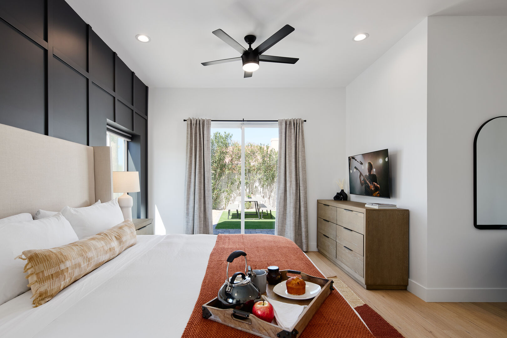 Spacious Primary Bedroom featuring a King Bed with a Smart TV, designer bedroom furnishings, backyard access and an ensuite Primary Bathroom.