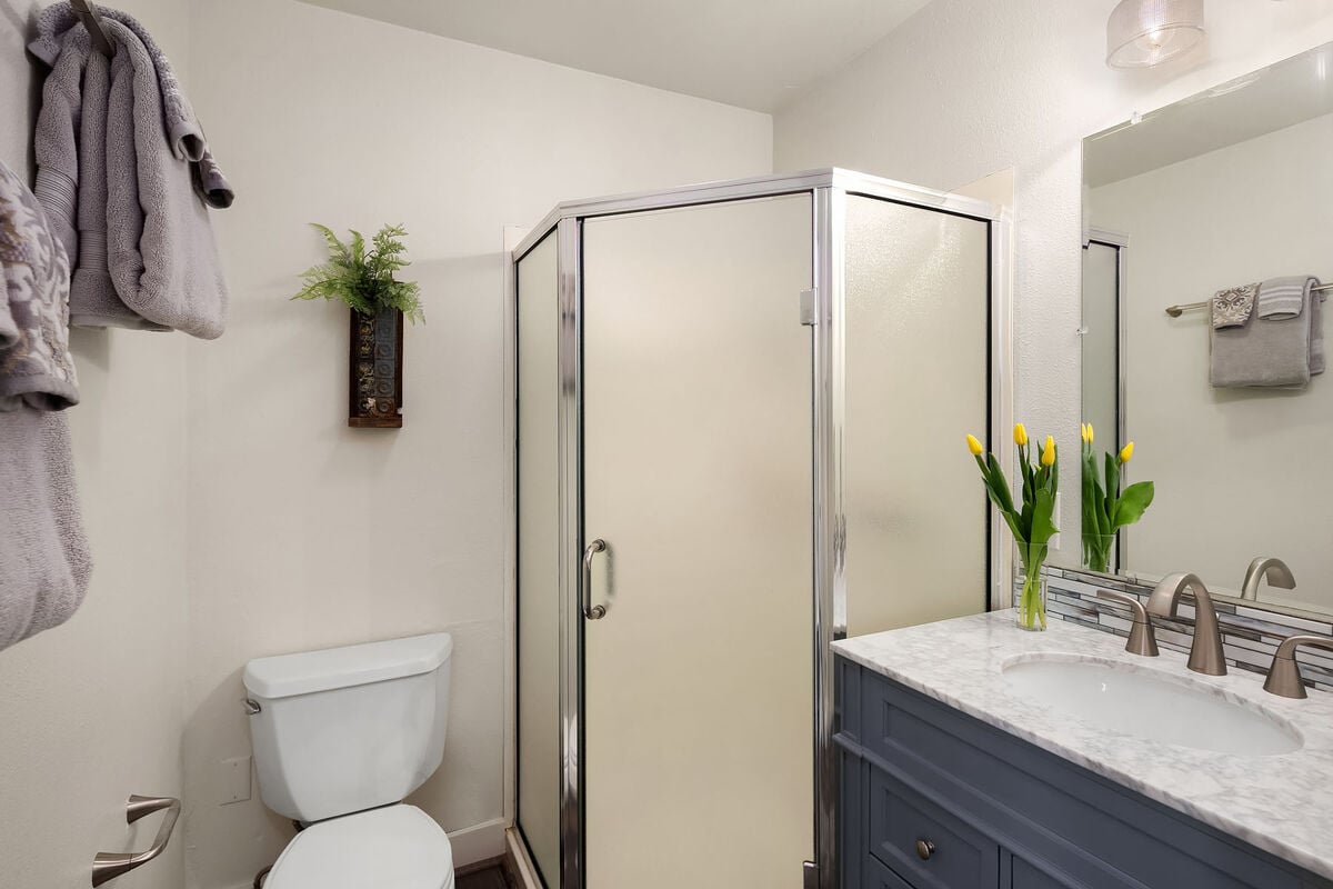 The en suite bathroom is attached to the primary bedroom. It features a shower, a toilet, and a marble-topped vanity.