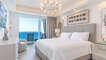 The first bedroom looks to over the waves, ands a king bed, dresser, chair, and custom lighting.