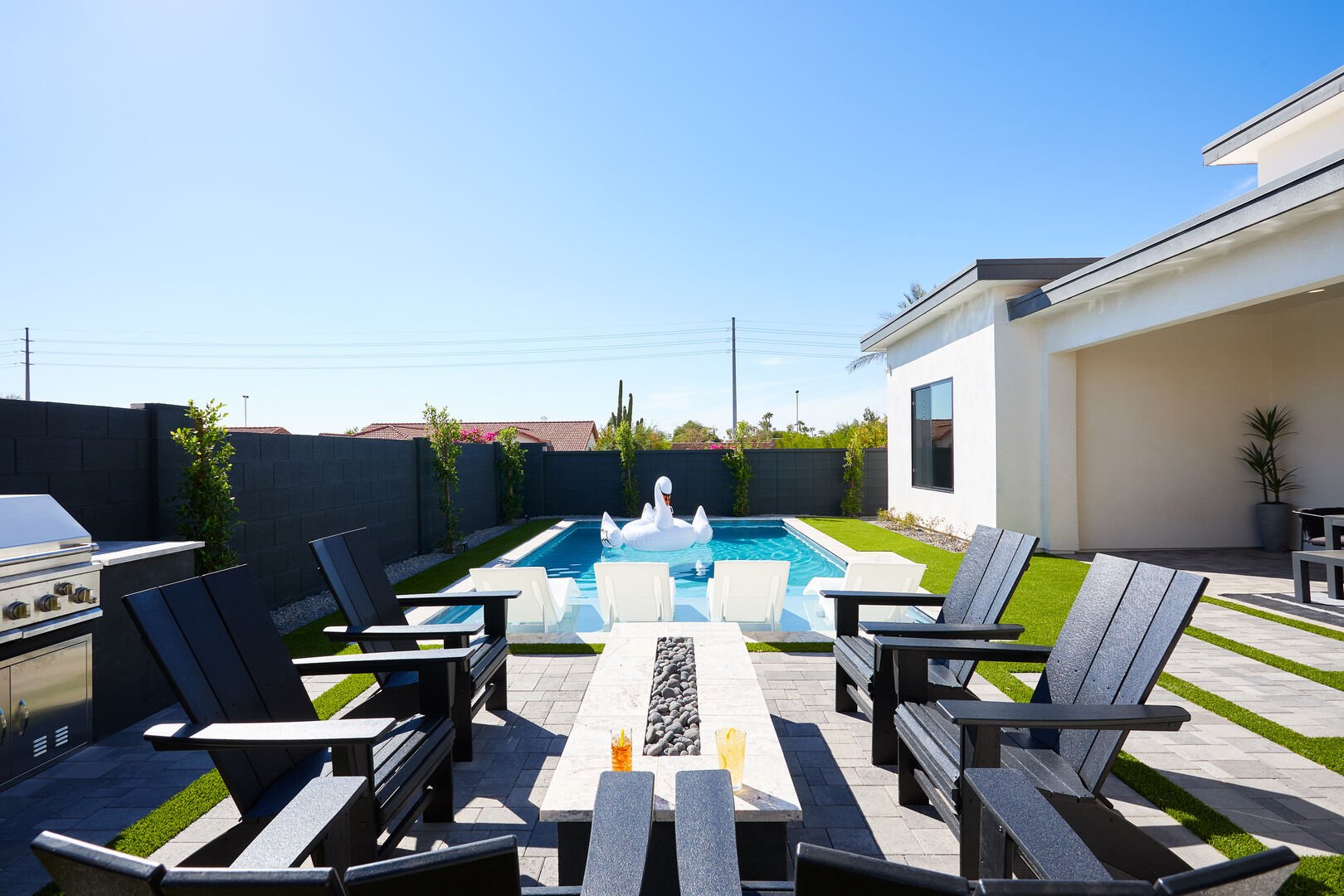 Unit 2: Resort-like backyard with a covered patio offering outdoor dining with seating for 8 guests, a sparkling blue heated pool with sun loungers, BBQ grill and a fire pit.