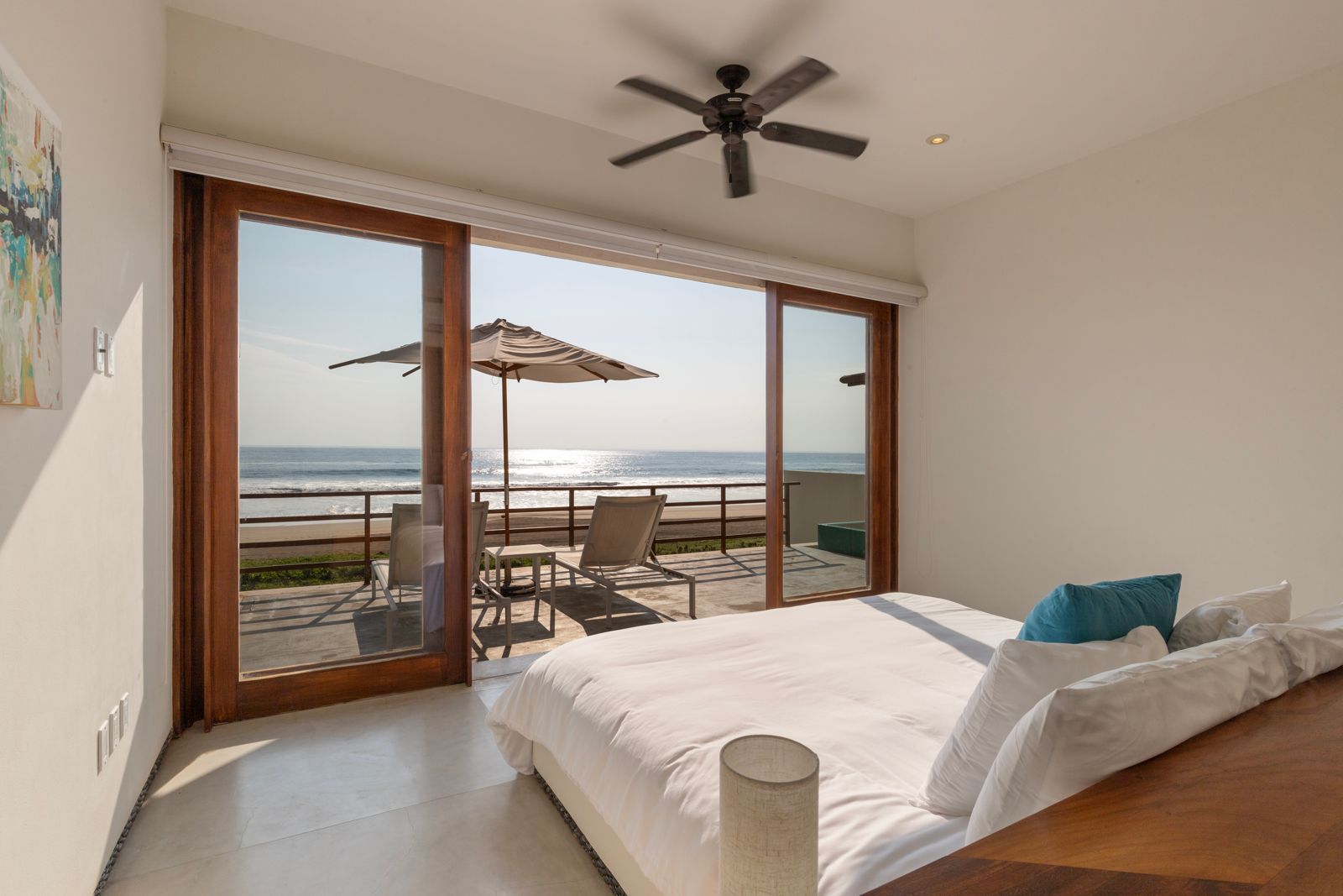 Wake up to the sound of waves in this inviting bedroom with direct balcony access and a warm, coastal ambiance.