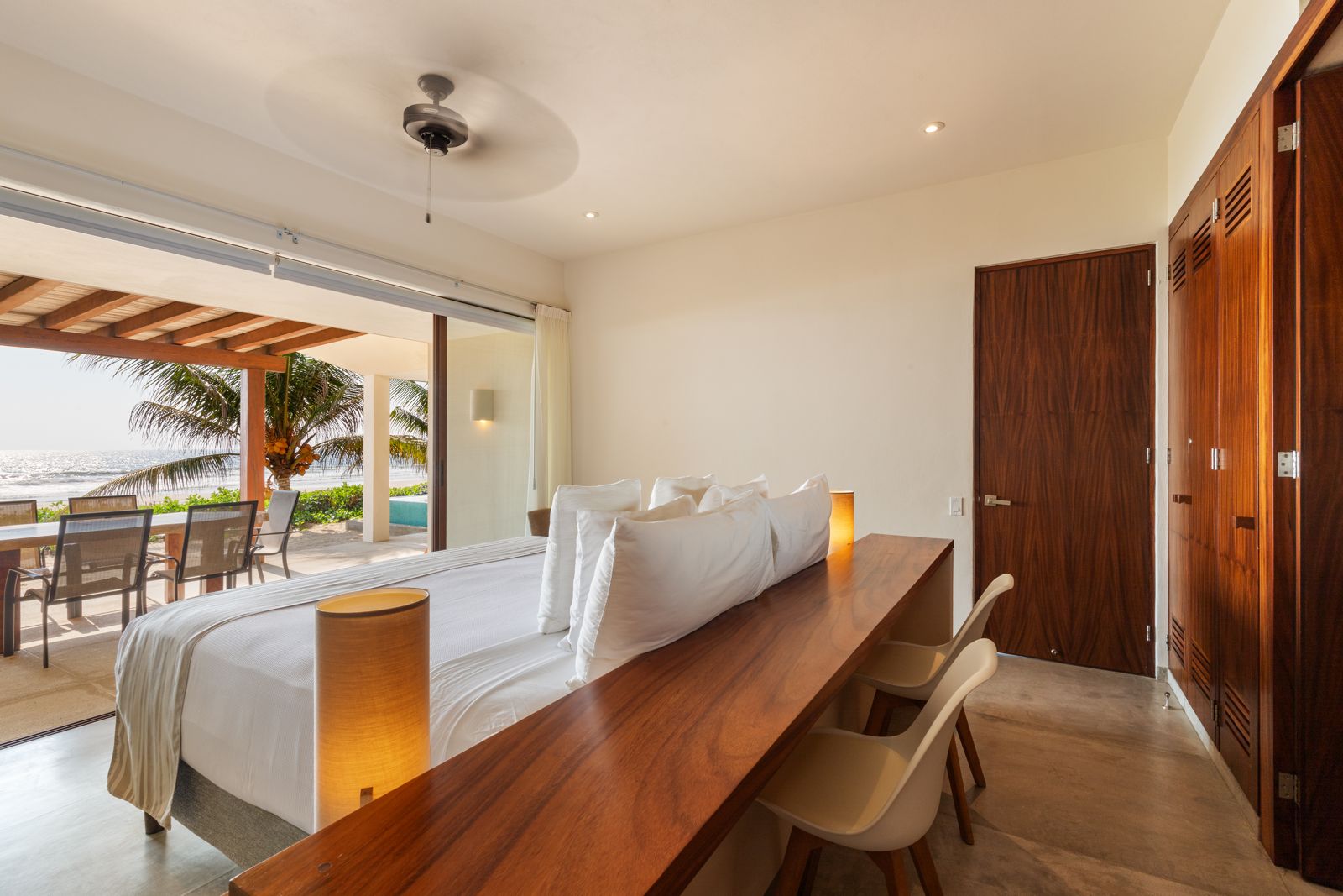 A beautifully designed bedroom featuring warm wooden tones, an oceanfront work desk, and direct access to a private terrace.