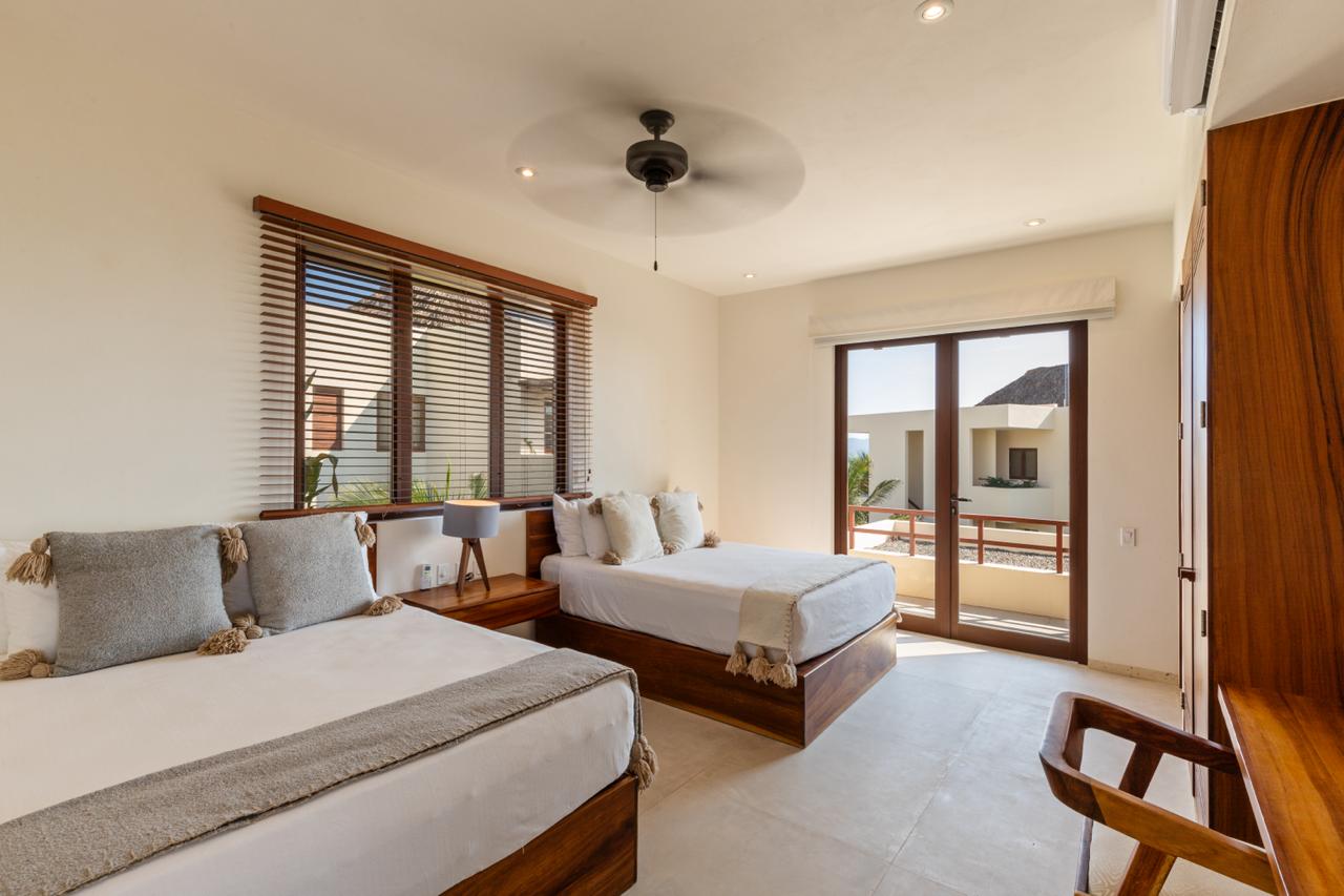 This elegantly designed twin bedroom offers comfort, large windows with garden views, and a warm, inviting atmosphere.