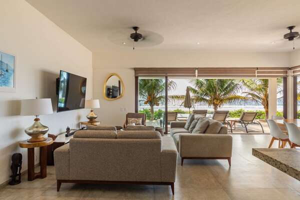 A stylish and inviting living space featuring plush seating, natural lighting, and seamless access to the oceanfront terrace.
