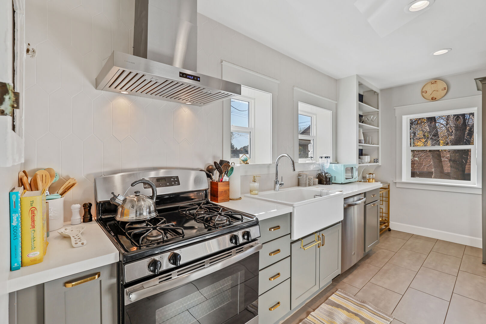 The kitchen features a gas stove, retro microwave, stainless steel appliances, and a charming farmhouse sink.