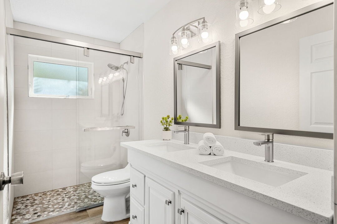 Brand new guest bathroom features a sleek double vanity and walk-in shower