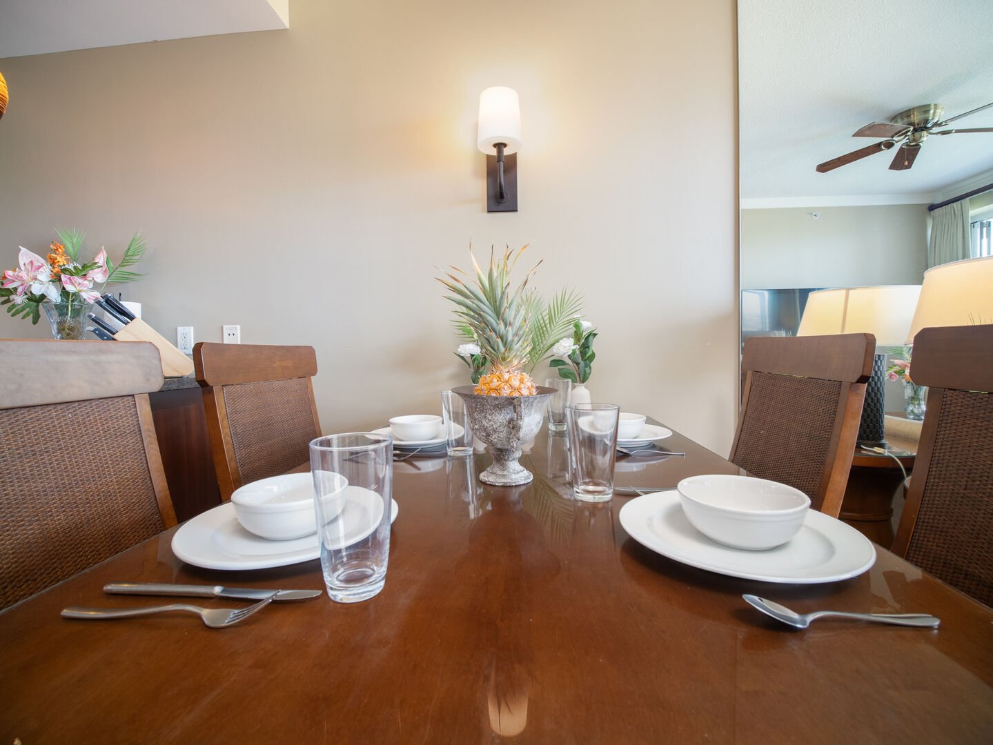 Dine in comfort with this sophisticated table setup, complete with tropical floral arrangements, cozy chairs, and plenty of natural light.