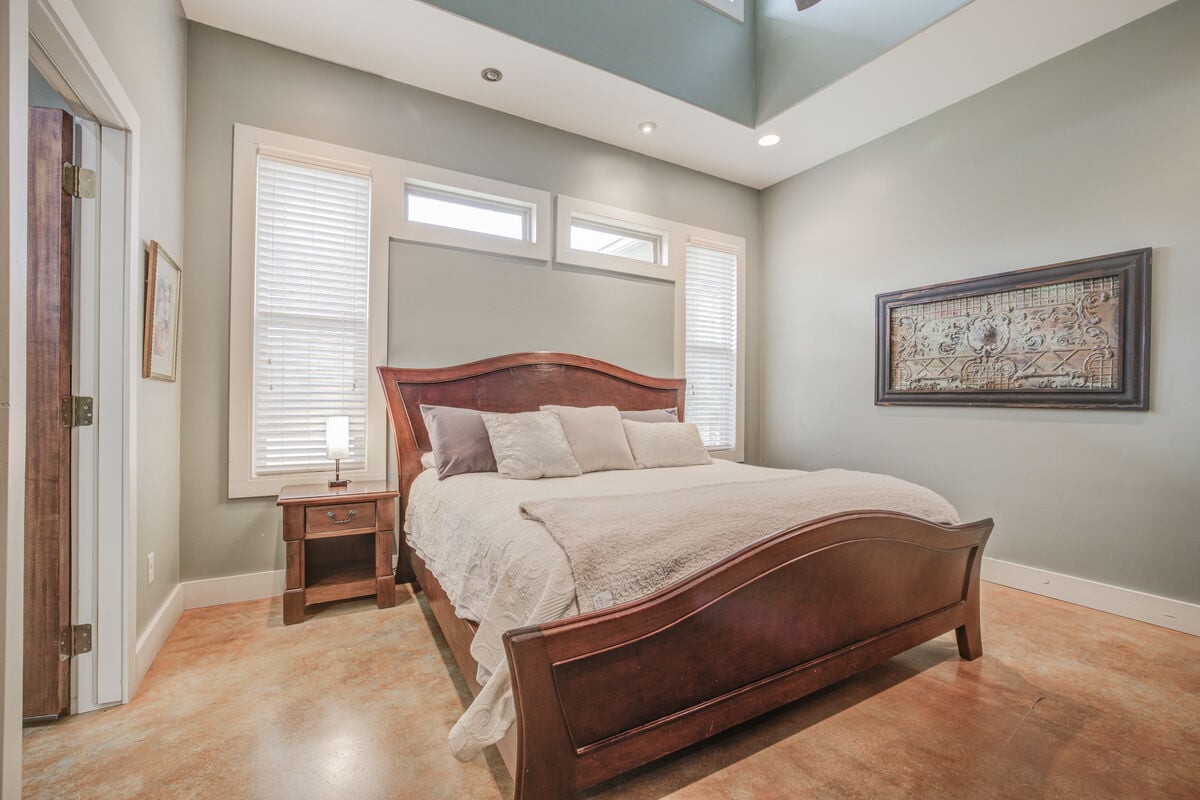 This primary bedroom offers charm and comfort with its soft bedding, natural light, and warm tones.