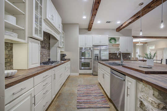 Fully equipped kitchen with stainless steel appliances, rustic beams, and ample counter space—perfect for cooking and gathering.